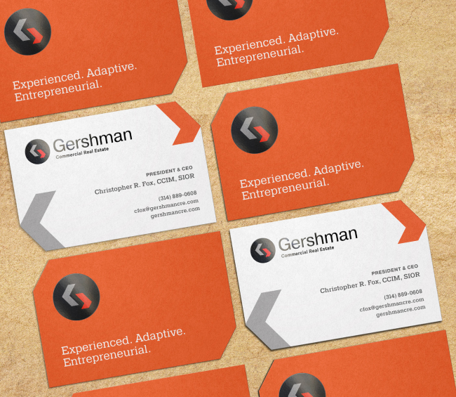 Business cards for Gershman Commercial Real Estate are arranged on a rustic surface. The cards are white and orange with geometric edges, company logo, contact details, and the slogan: Experienced. Adaptive. Entrepreneurial.