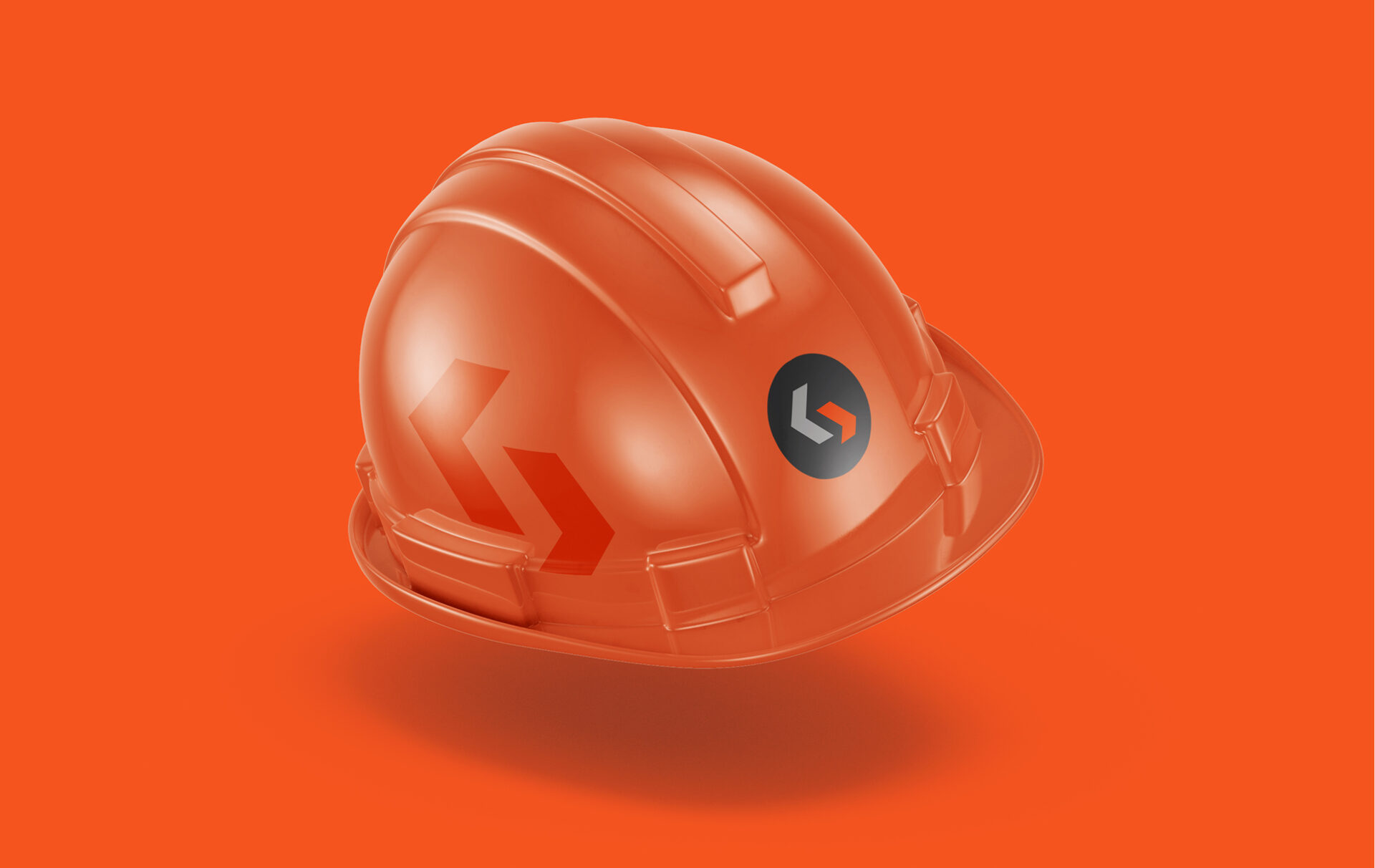 An orange construction hard hat with a black and orange logo and arrow design sits against an orange background.