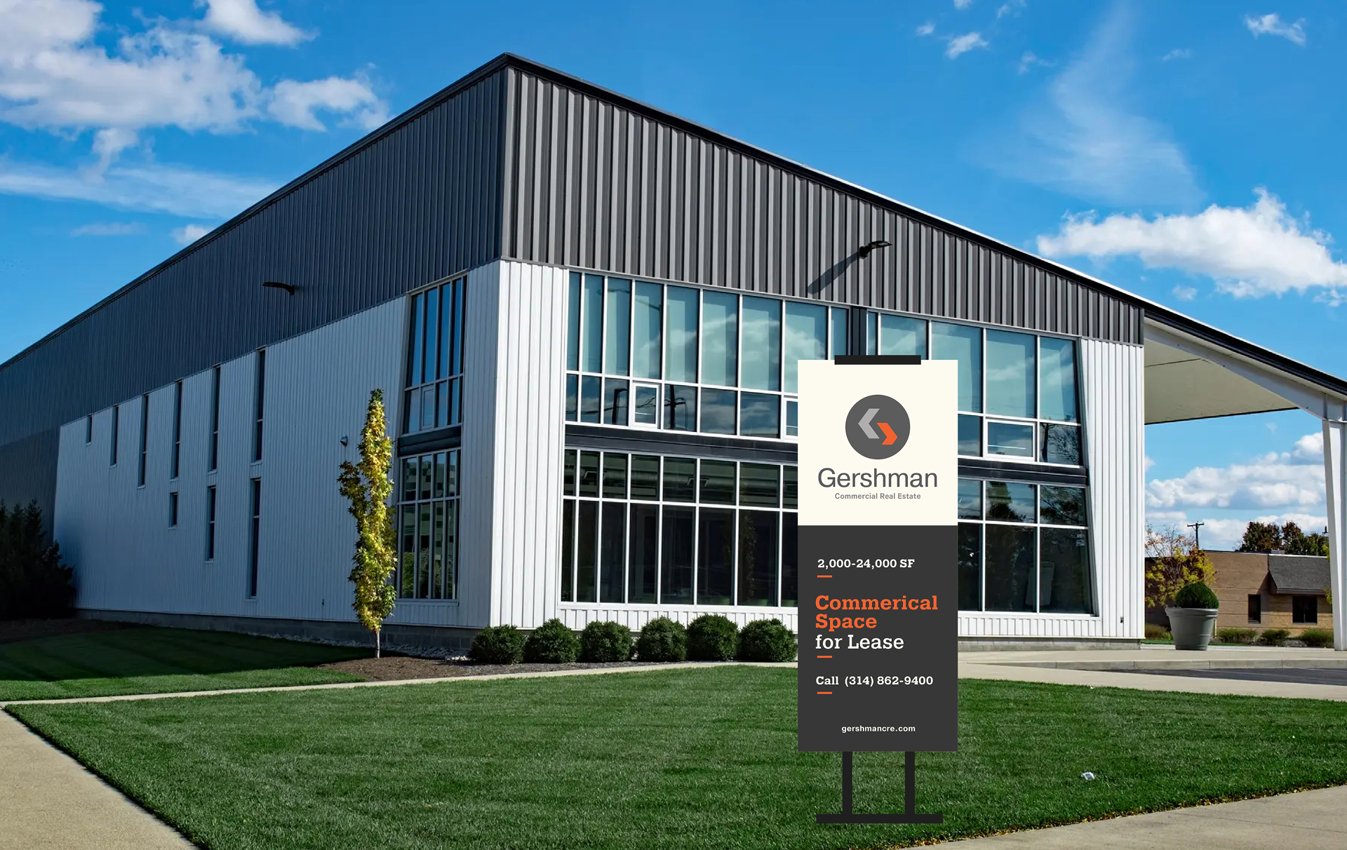 Modern commercial building with large glass windows and metal siding. A sign in front reads, “Gershman Commercial Real Estate—Commercial Space for Lease” with contact info and a landscaped lawn.
