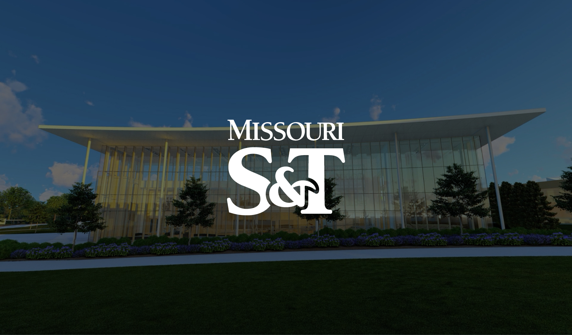 A modern glass building with tall columns and surrounding greenery, featuring the Missouri S&T logo prominently in the center.