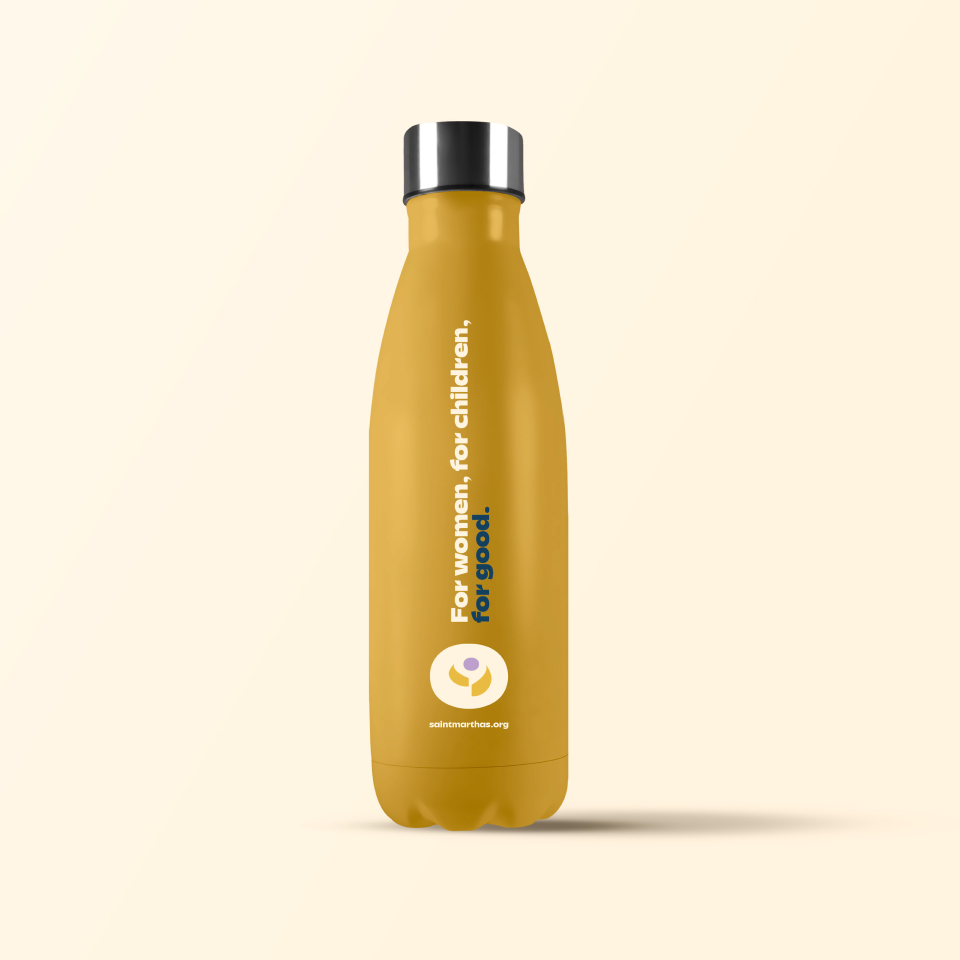 A mustard yellow reusable water bottle with a silver cap, featuring the text For women. For children. For good. and a circular logo with a website address at the bottom, all on a light background.
