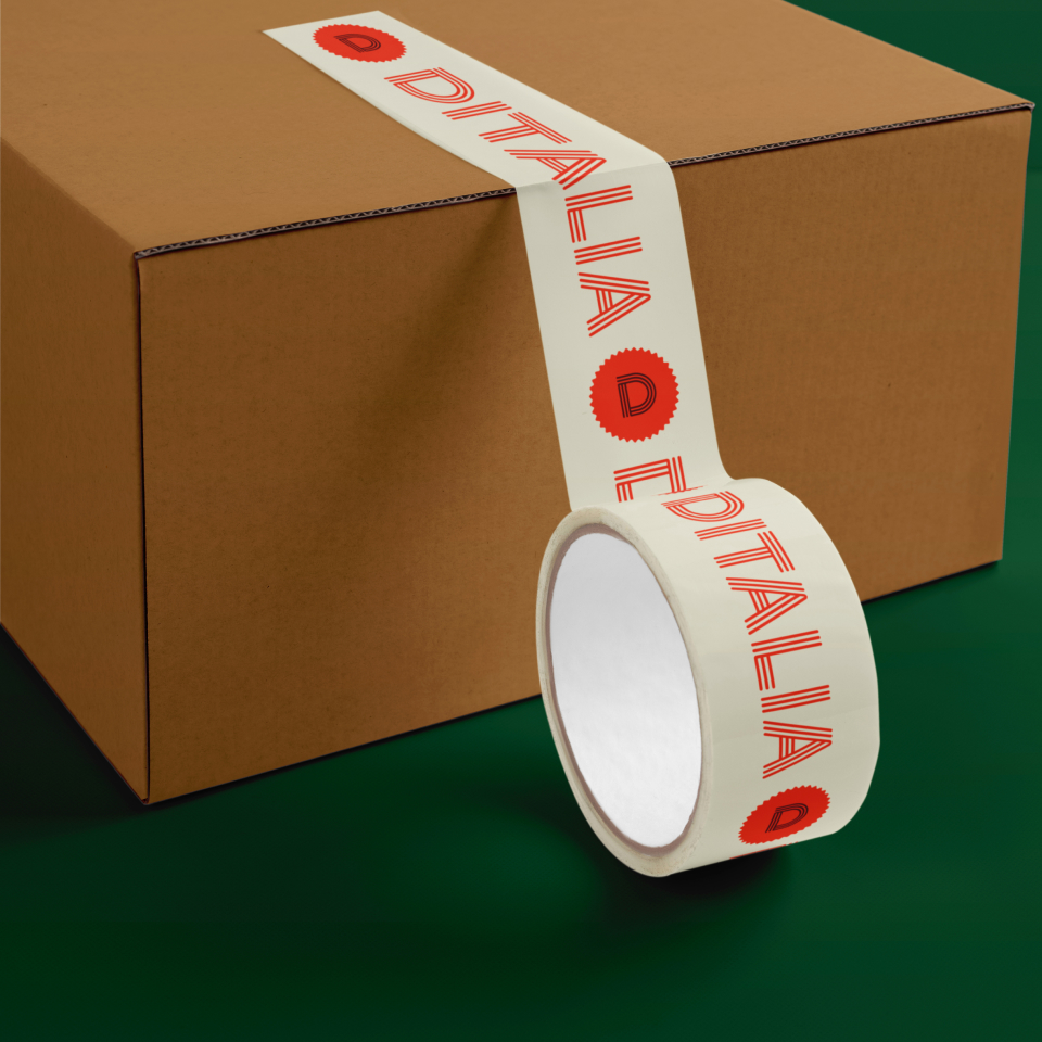 A roll of branded tape reading DITALIA with red text and logo is partially unrolled and attached to a closed brown cardboard box on a green background.