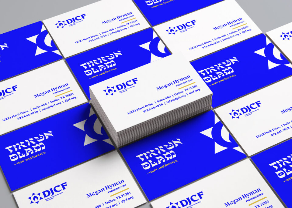 A stack of business cards on a surface covered with more cards. The cards feature the DICF logo, a blue Star of David, and blue text on a white background, with contact details for Megan Hyman, Executive Director.