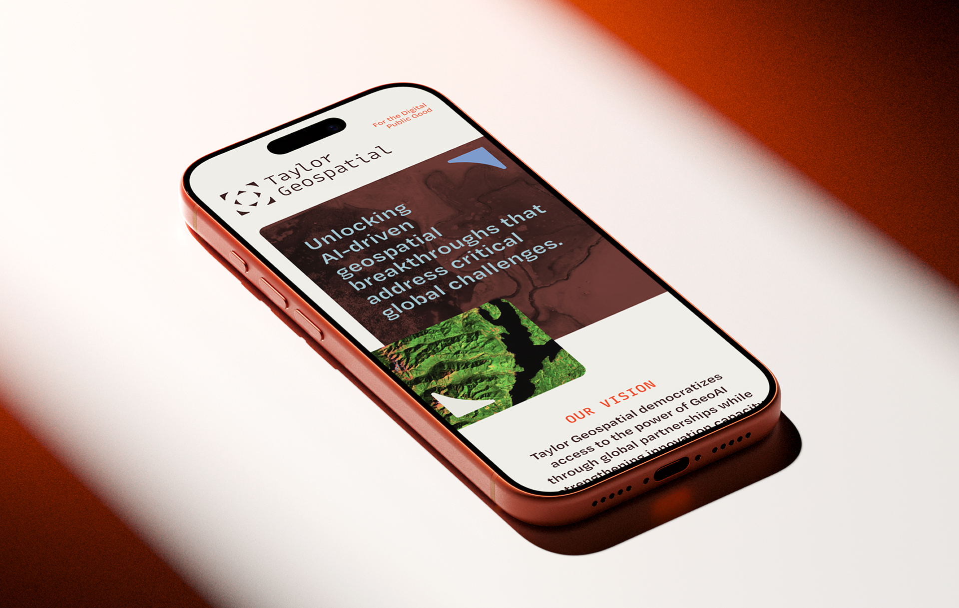 taylor-geospatial-website-mobile - Sprehe Studio A smartphone displaying the Taylor Geospatial website homepage, featuring the companys logo, tagline about addressing global challenges, and an aerial image of green terrain. The phone has a red case and is placed on a light surface.